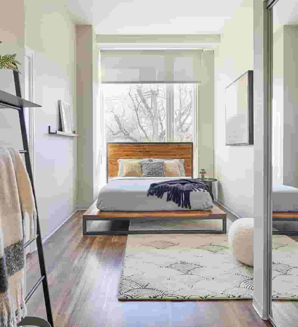 Wood-style flooring in bedroom with large window behind bed